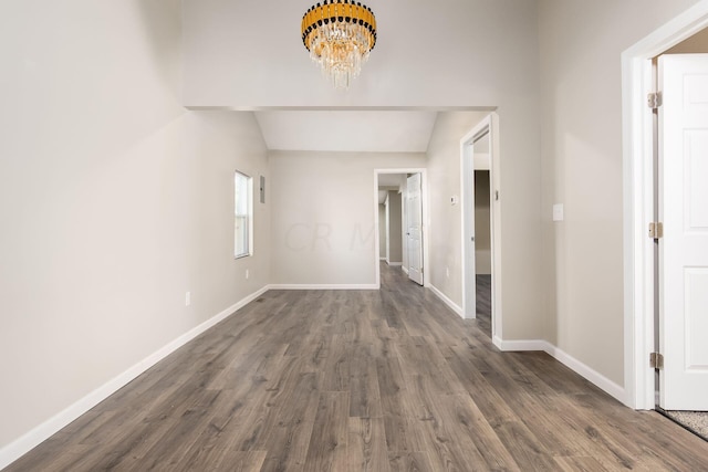 hallway with a chandelier, dark wood-type flooring, and lofted ceiling