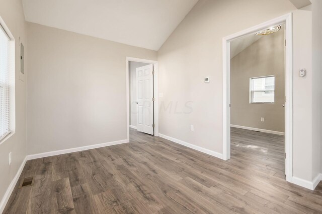 unfurnished room featuring hardwood / wood-style flooring and vaulted ceiling