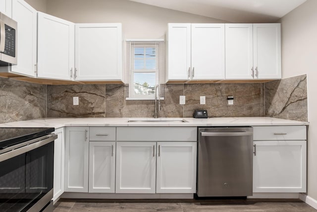 kitchen with stainless steel appliances, white cabinetry, lofted ceiling, and sink