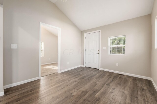 spare room with dark hardwood / wood-style floors and vaulted ceiling