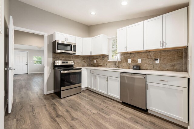 kitchen with white cabinetry, sink, light wood-type flooring, and appliances with stainless steel finishes