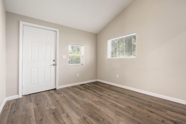 unfurnished room with vaulted ceiling and dark wood-type flooring