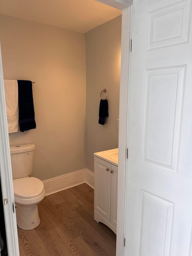 bathroom with toilet, vanity, and hardwood / wood-style flooring