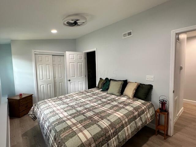 bedroom with hardwood / wood-style flooring, vaulted ceiling, and a closet