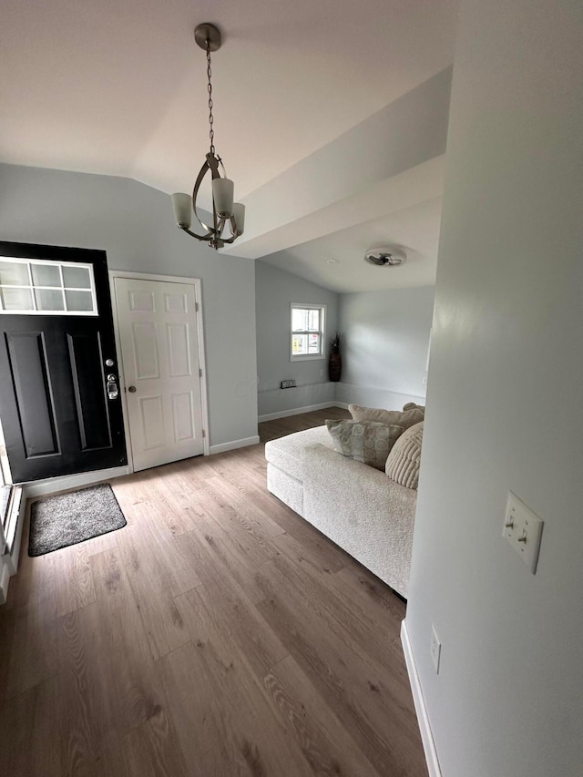 entryway with a chandelier, vaulted ceiling, and hardwood / wood-style flooring