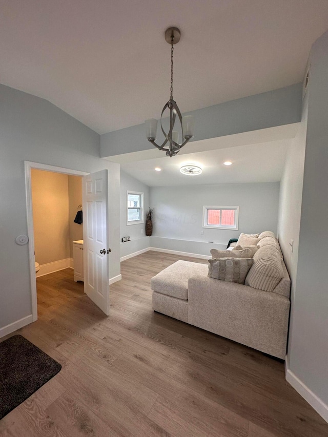 living room featuring an inviting chandelier, vaulted ceiling, and hardwood / wood-style flooring