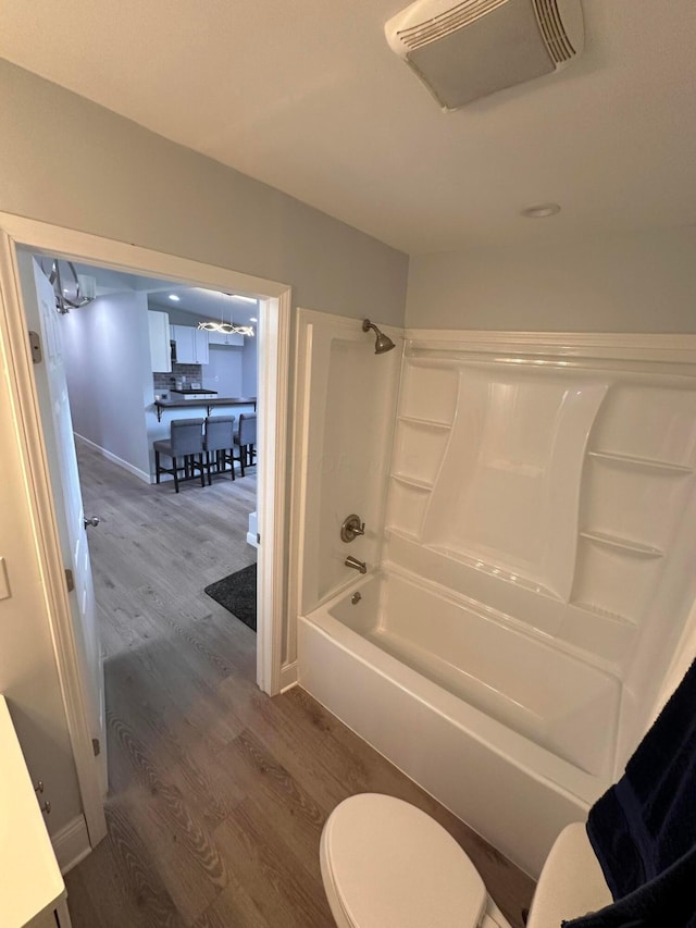 bathroom featuring toilet, washtub / shower combination, and hardwood / wood-style flooring