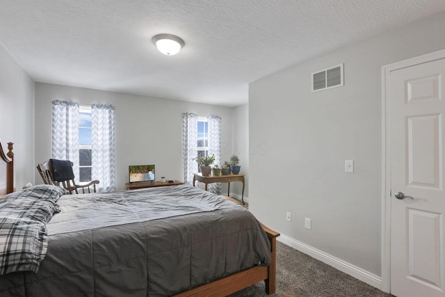 bedroom with a textured ceiling, multiple windows, and carpet floors