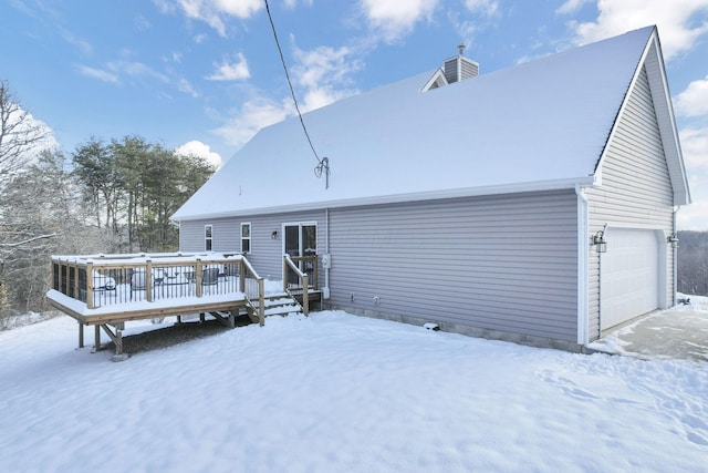 snow covered house featuring a garage and a wooden deck