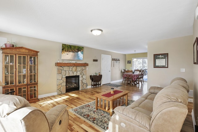 living room with hardwood / wood-style floors and a stone fireplace