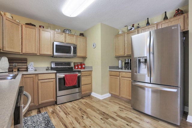 kitchen with light hardwood / wood-style floors, stainless steel appliances, sink, and light brown cabinets