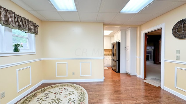 empty room with hardwood / wood-style flooring and a paneled ceiling