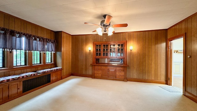 interior space featuring wood walls, ceiling fan, and light carpet