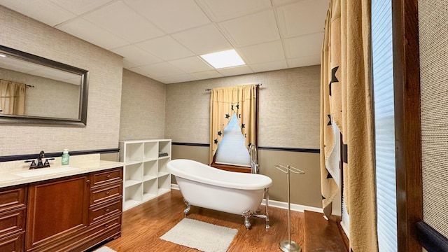 bathroom featuring hardwood / wood-style floors, a washtub, a drop ceiling, and vanity