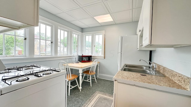 kitchen featuring dark colored carpet, white range with gas stovetop, and sink