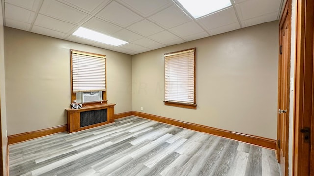 spare room with a drop ceiling, cooling unit, and light hardwood / wood-style floors