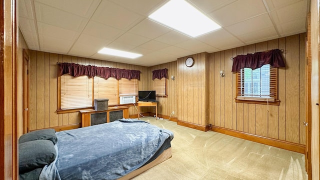 carpeted bedroom with wood walls, a drop ceiling, and cooling unit