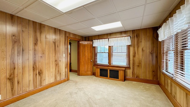 unfurnished room featuring light carpet, radiator heating unit, and wooden walls