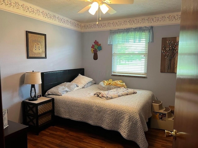 bedroom with ceiling fan, dark hardwood / wood-style flooring, and a textured ceiling