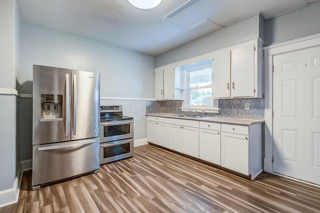 kitchen featuring white cabinets, sink, decorative backsplash, light hardwood / wood-style floors, and stainless steel appliances