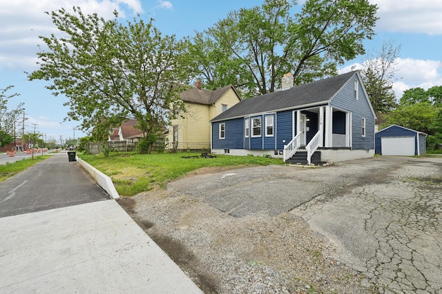 bungalow with covered porch, a garage, a front lawn, and an outdoor structure