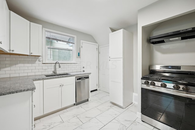 kitchen with decorative backsplash, stainless steel appliances, sink, dark stone countertops, and white cabinetry