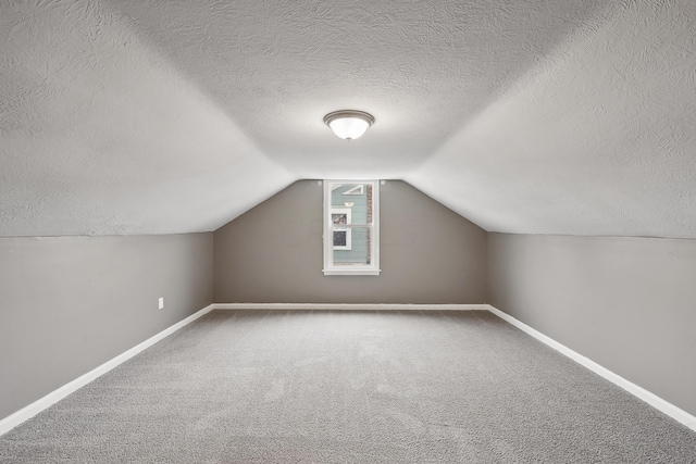 bonus room with carpet flooring, vaulted ceiling, and a textured ceiling