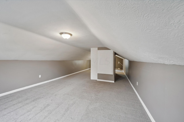 bonus room with carpet floors, a textured ceiling, and vaulted ceiling