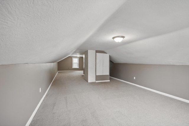 bonus room with a textured ceiling, light carpet, and vaulted ceiling