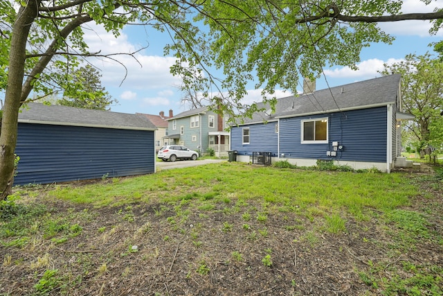 rear view of property with a lawn and central air condition unit