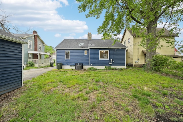 rear view of house featuring cooling unit and a lawn