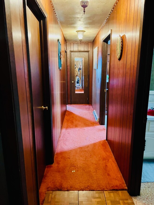 hallway with a textured ceiling and wooden walls