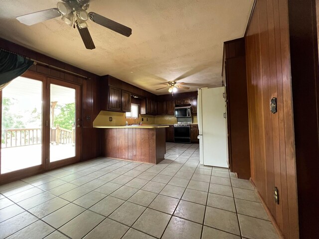 kitchen featuring wooden walls, white refrigerator, kitchen peninsula, and light tile patterned floors