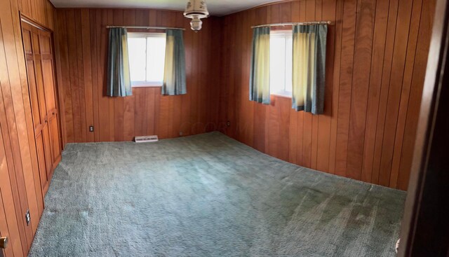 carpeted empty room featuring wooden walls