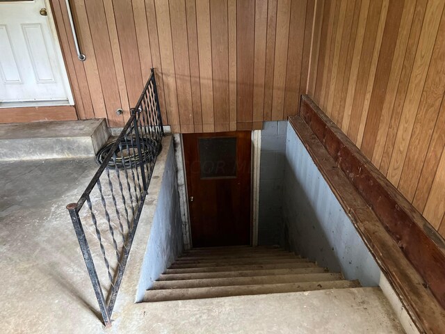 stairway featuring wooden walls and concrete floors