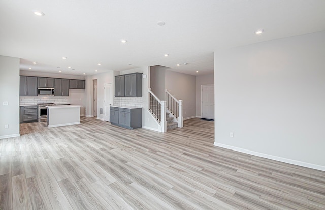 unfurnished living room with light wood finished floors, stairs, baseboards, and recessed lighting