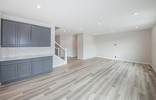 interior space featuring baseboards, stairs, recessed lighting, and light wood finished floors