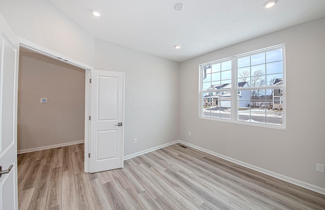 empty room with baseboards, light wood-style flooring, and recessed lighting