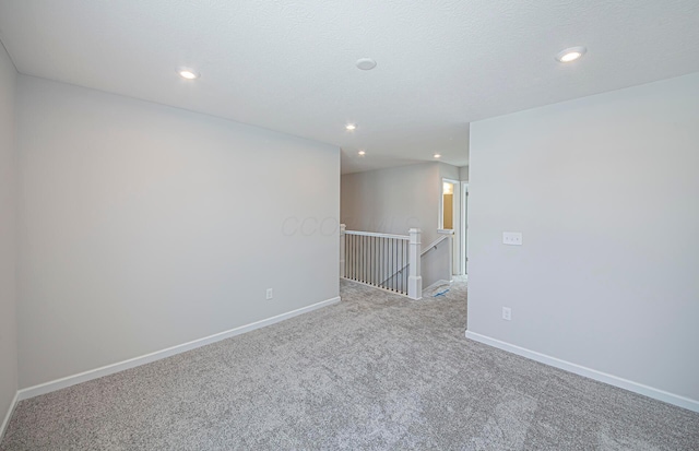 carpeted empty room featuring baseboards, recessed lighting, and a textured ceiling