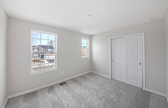 unfurnished bedroom featuring baseboards, visible vents, a closet, and carpet floors
