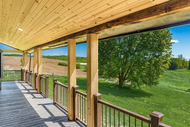 wooden deck featuring a lawn, covered porch, and a rural view