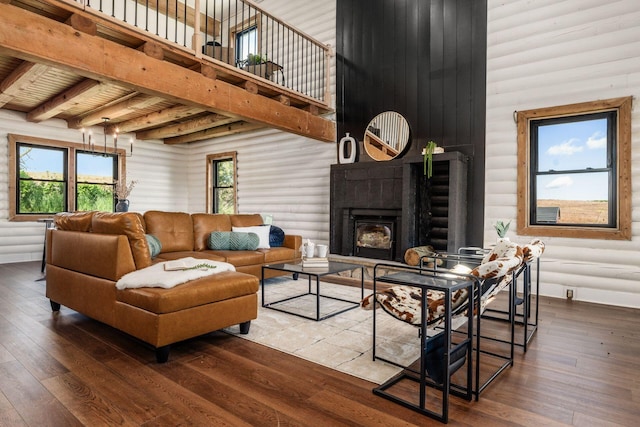 living room featuring beam ceiling, wood-type flooring, and a towering ceiling