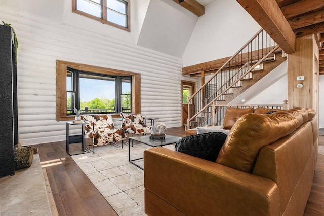 living room with beam ceiling, log walls, high vaulted ceiling, and light wood-type flooring