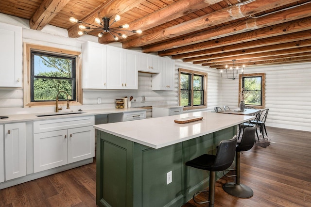 kitchen featuring white cabinets, sink, a notable chandelier, a kitchen island, and dark hardwood / wood-style flooring