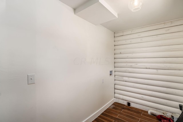 laundry room featuring log walls, washer hookup, and dark hardwood / wood-style flooring