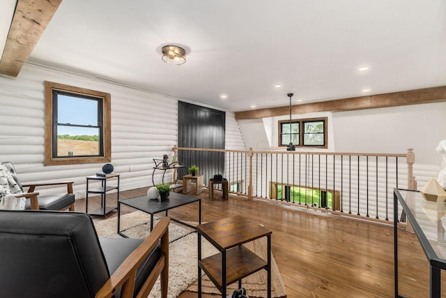 living room with beam ceiling, wood-type flooring, and rustic walls