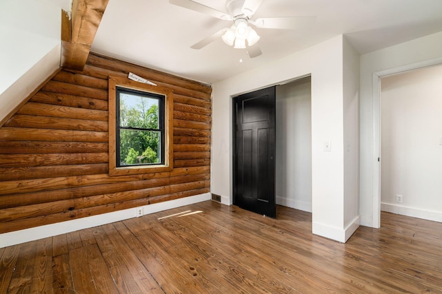 unfurnished bedroom featuring log walls, hardwood / wood-style floors, a closet, and ceiling fan