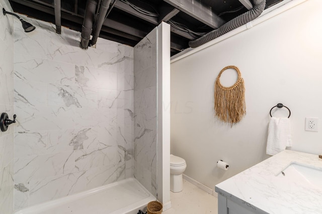 bathroom with tiled shower, vanity, and toilet