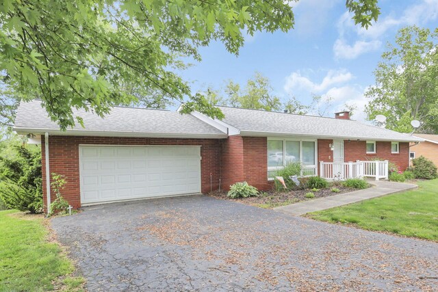 single story home featuring a front yard, a porch, and a garage