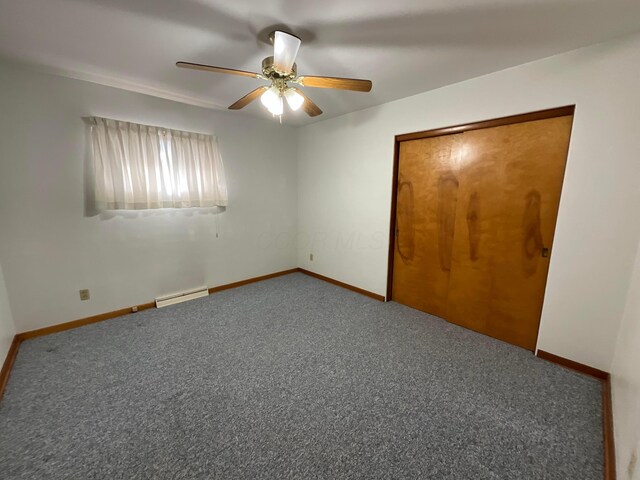 unfurnished bedroom with baseboard heating, ceiling fan, a closet, and carpet